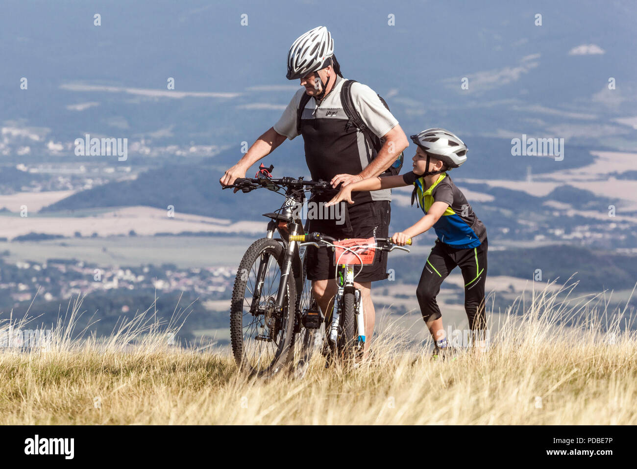 Ciclisti in bicicletta su un sentiero di montagna, padre e figlio, montagna Velka Javorina, confine ceco-slovacco in White Carpathians Man spingendo la bicicletta in salita Foto Stock