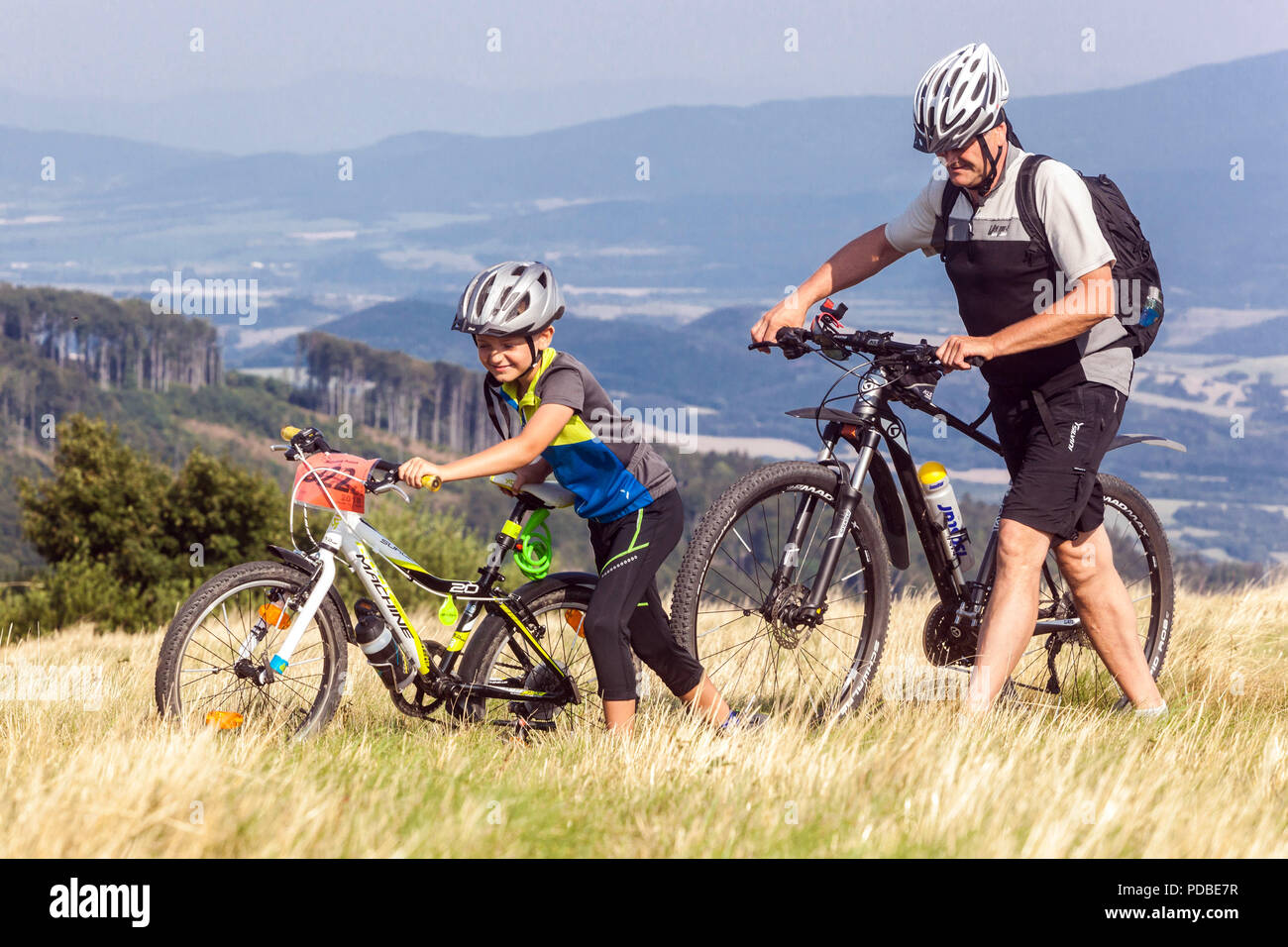 Padre e figlio che spingono le biciclette, i motociclisti che pedalano su un sentiero di montagna, la montagna Velka Javorina, il confine ceco-slovacco nei Carpazi bianchi Foto Stock
