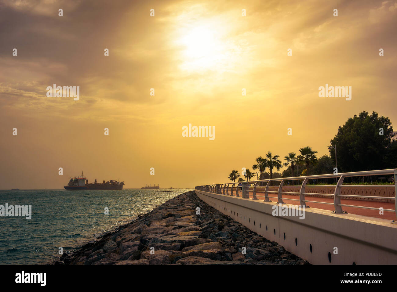 Contenitore di carico nave lasciando Dubai Marina al tramonto Foto Stock