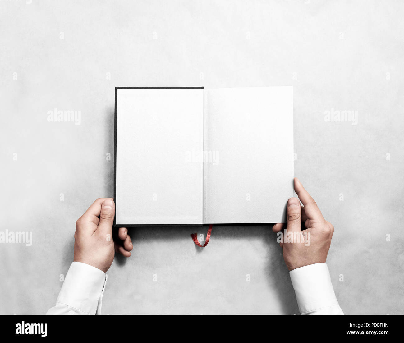 Mano azienda blank libro aperto mock up con metà bianca titolo. Persona la lettura di vuoto paperback mockup. Notebook nero all'interno del modello. Progettazione di pubblicazione frondeggiare dell'uomo. Libro di testo diffuso con segnalibro. Foto Stock