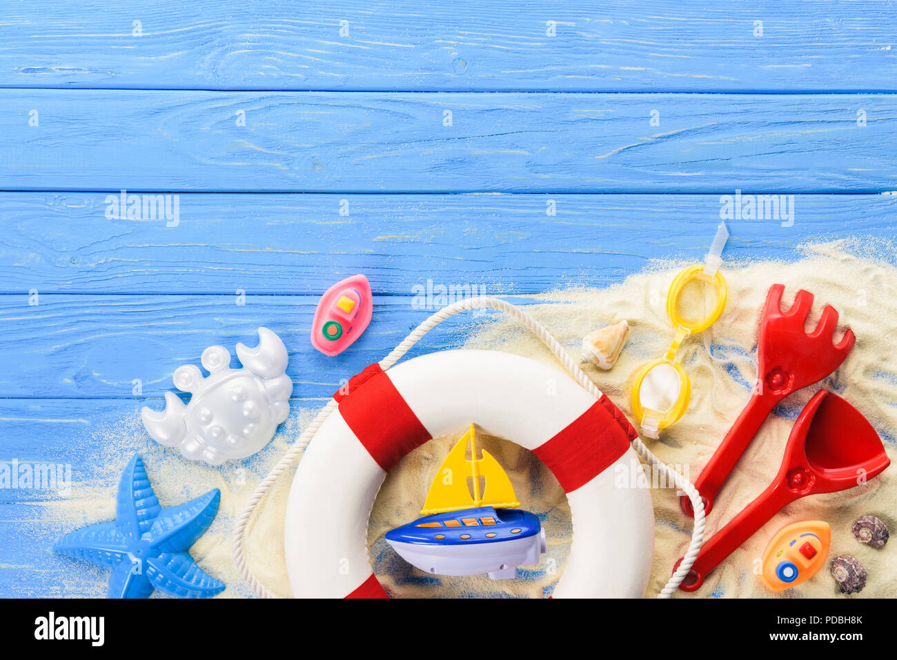 Anello di vita e giocattoli da spiaggia blu su sfondo di legno Foto Stock