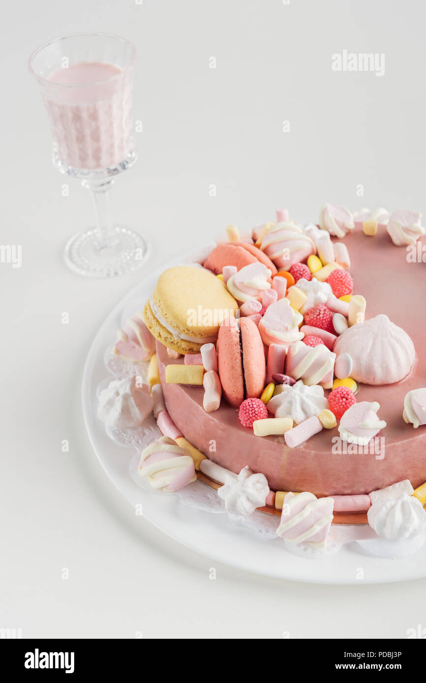Torta rosa con marshmallows e macarons sulla piastra e frullato in vetro Foto Stock