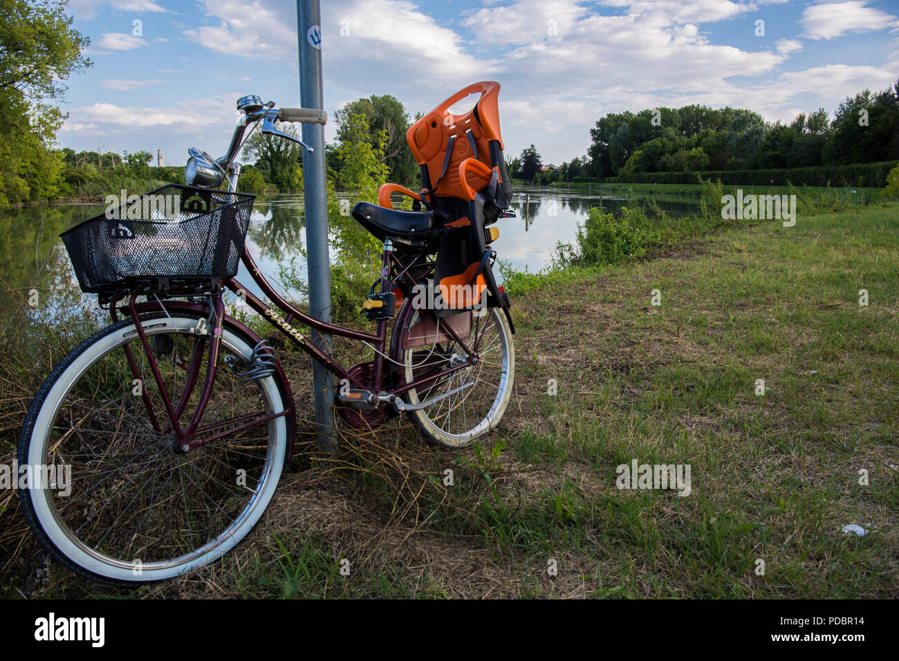 Una city bike appoggiato sul palo vicino a un fiume Foto Stock