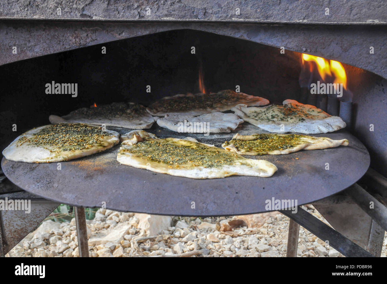 Cucina Outdoor preparare un piatto Pane Pita su un Saj - un ferro a forma di cupola pan che viene utilizzato per cuocere il pane pita. Esso è posizionato sopra una fonte di h Foto Stock