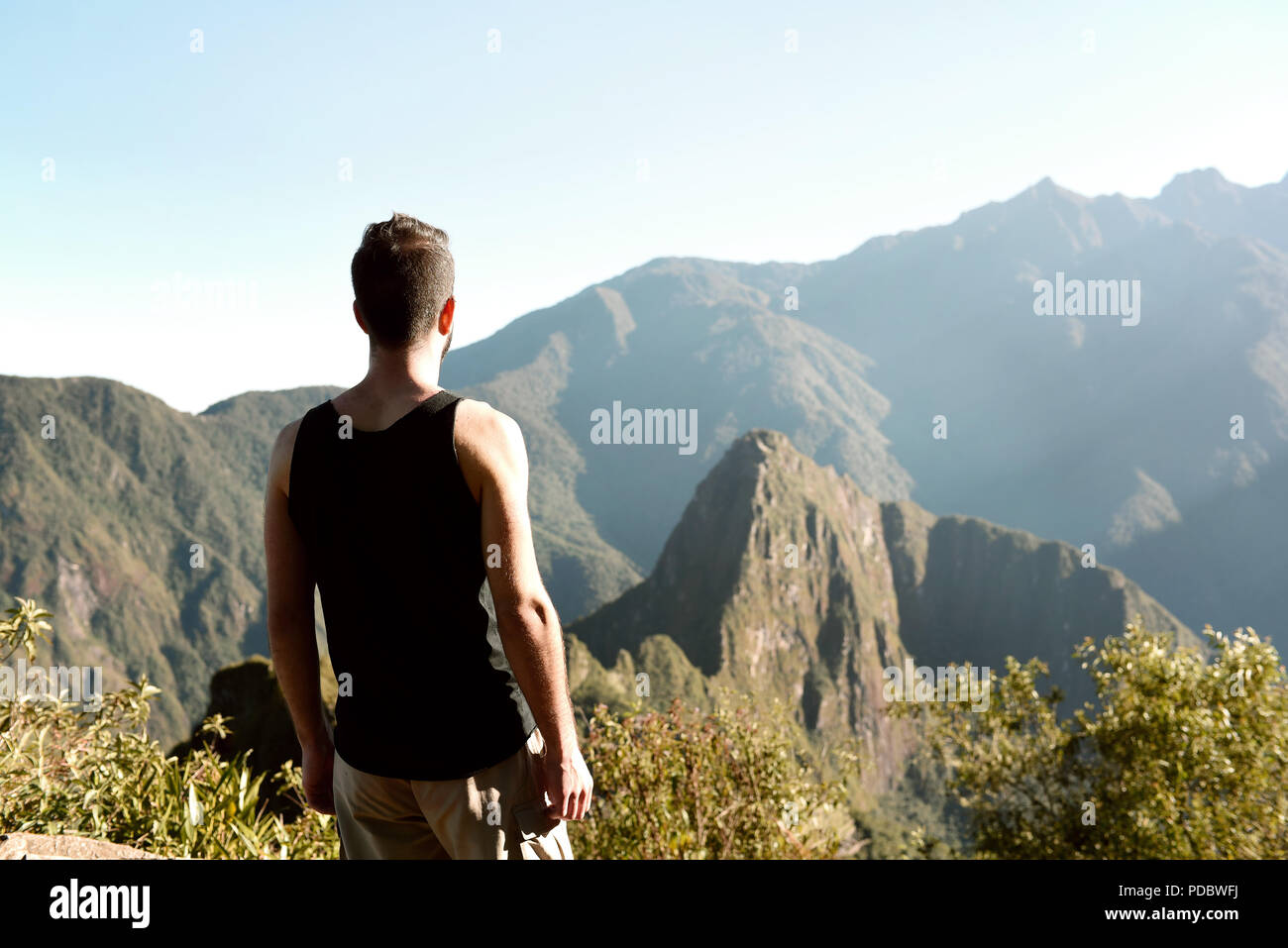 Da ragazzo dietro, in piedi sul Machu Picchu Mountain guardando Huayna Picchu mountain e antica città di Machu Picchu. Lug 2018 Foto Stock
