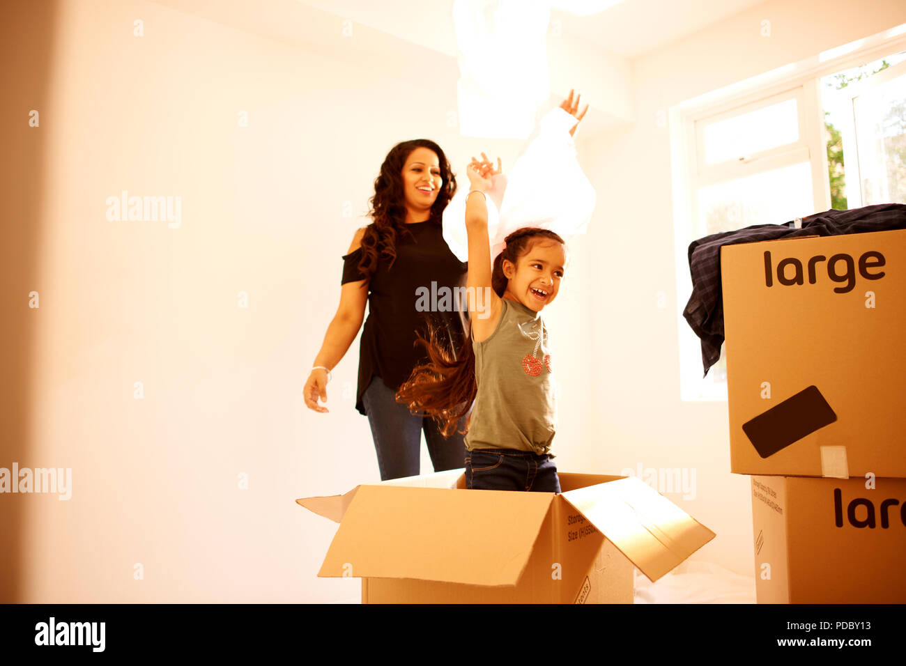 Giocoso madre e figlia in movimento nella nuova casa Foto Stock