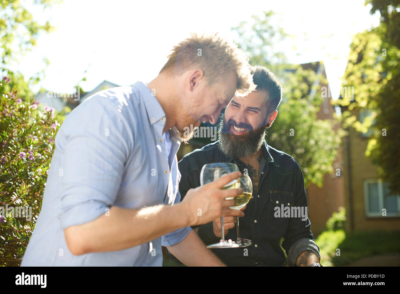 Maschio felice coppia gay di bere vino in giardino soleggiato Foto Stock