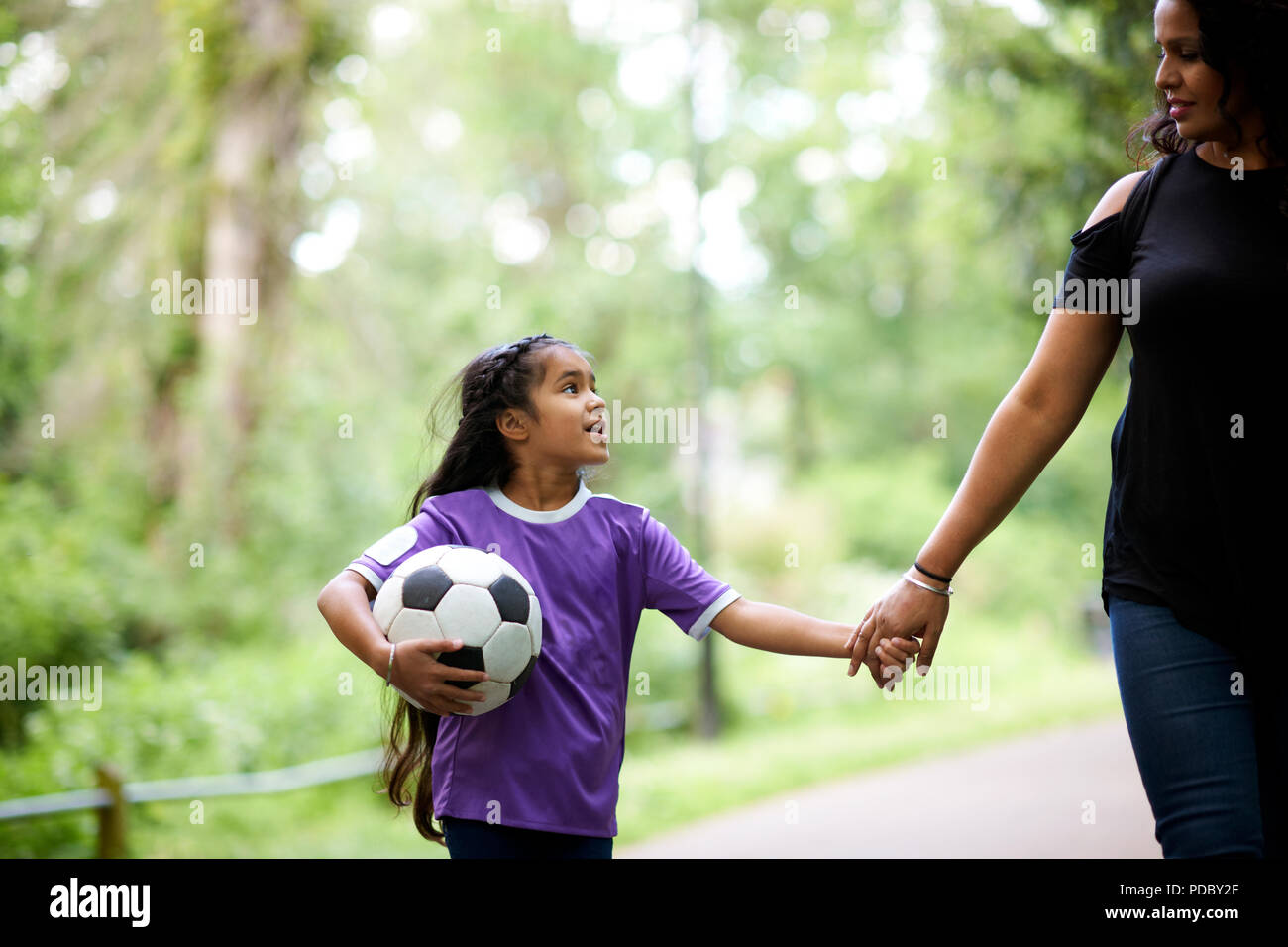 Affettuosa madre e figlia con pallone da calcio tenendo le mani Foto Stock