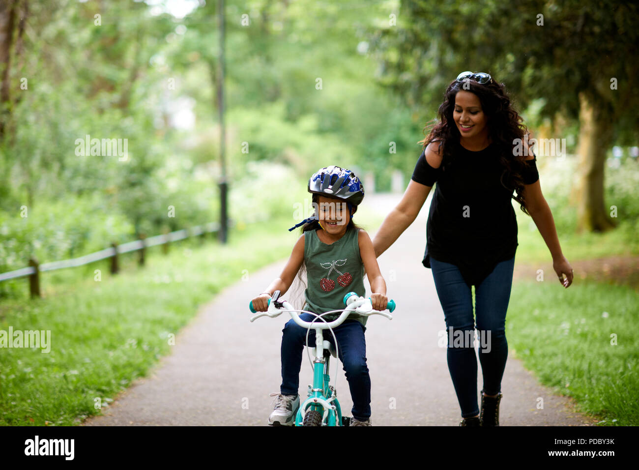 Felice madre figlia di insegnamento come per correre in bici Foto Stock