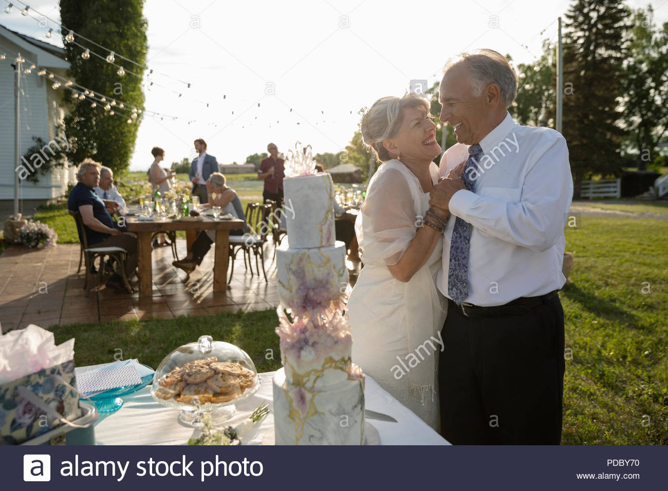 Affettuosa senior sposa e lo sposo in piedi alla torta di nozze Foto Stock