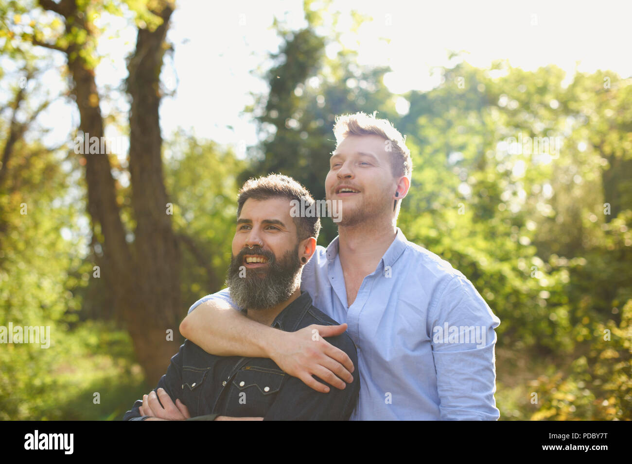 Affettuoso gay maschio giovane costeggiata nel soleggiato parco Foto Stock