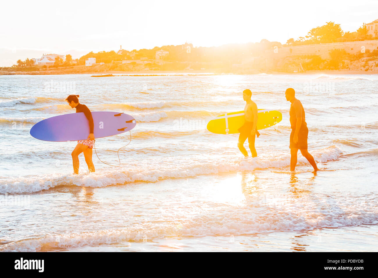 Maschio di surfers che trasportano le tavole da surf in oceano su sunny beach Foto Stock