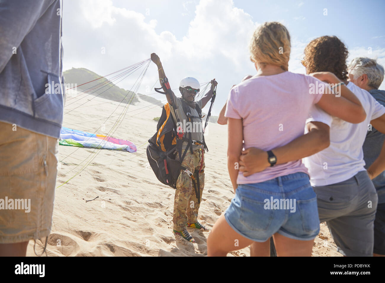Gli studenti guardando maschio istruttore di parapendio con apparecchiature a sunny beach Foto Stock