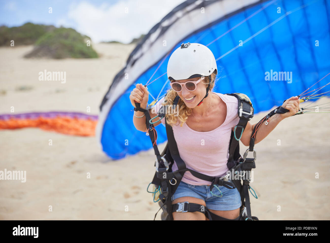 Donna sorridente parapendio con paracadute sulla spiaggia Foto Stock