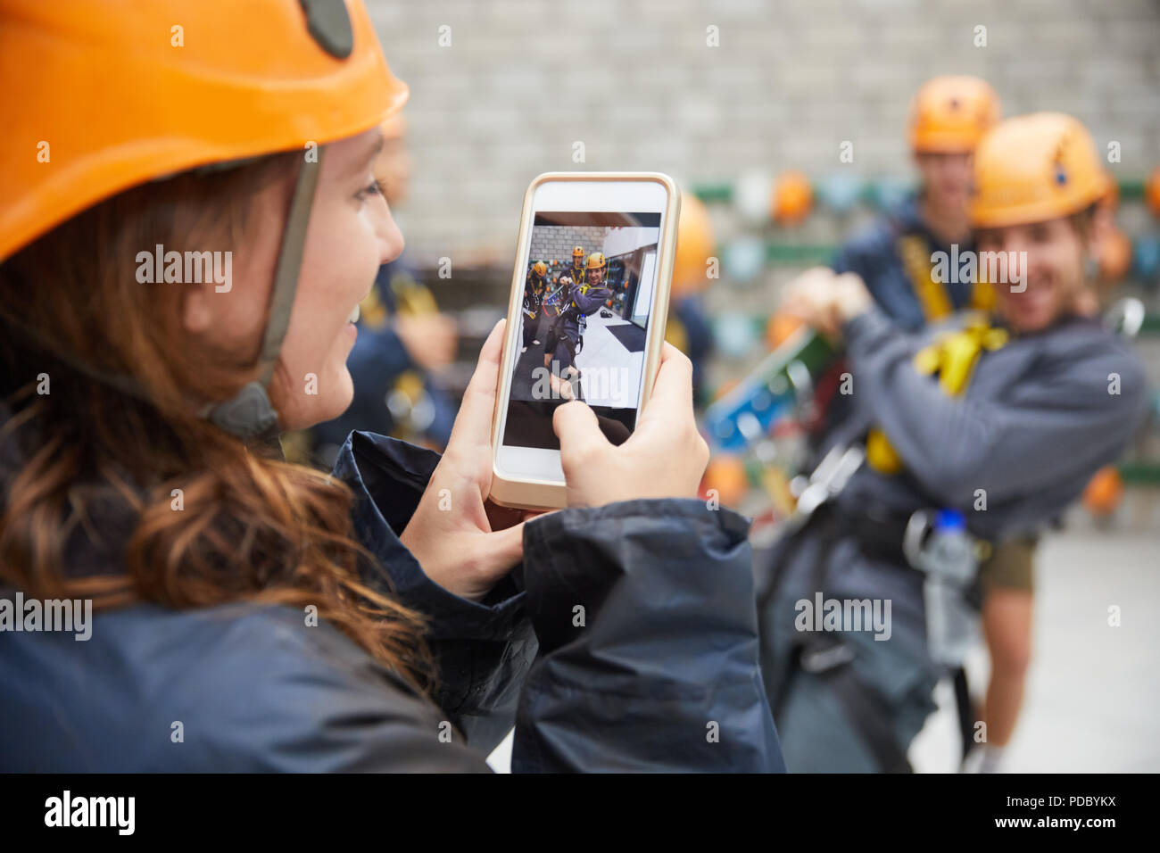 Donna con la fotocamera del telefono a fotografare gli amici in zip apparecchiature della linea Foto Stock