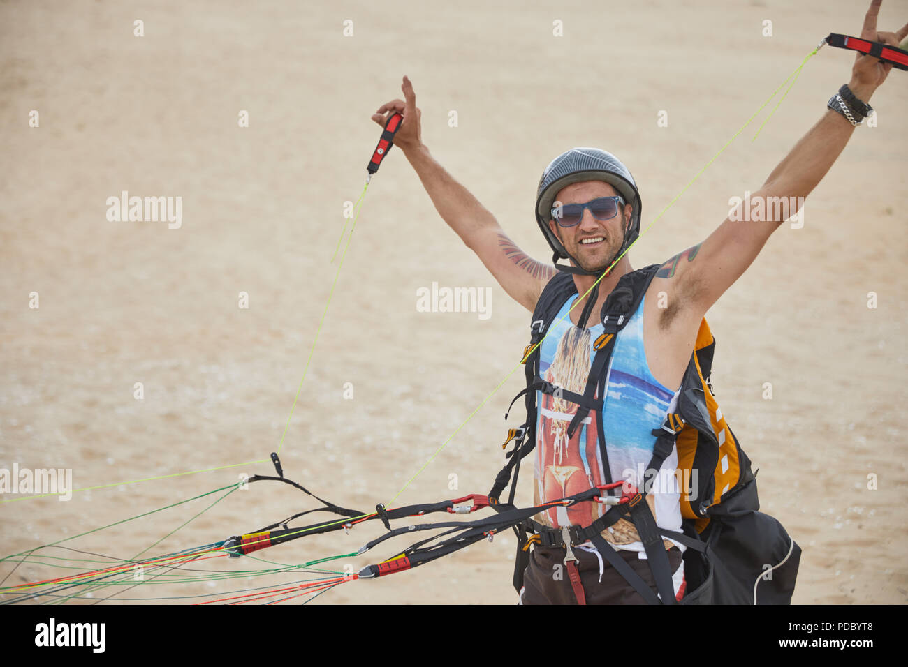Ritratto fiduciosi, spensierata maschio reggiate di parapendio con attrezzatura sulla spiaggia Foto Stock