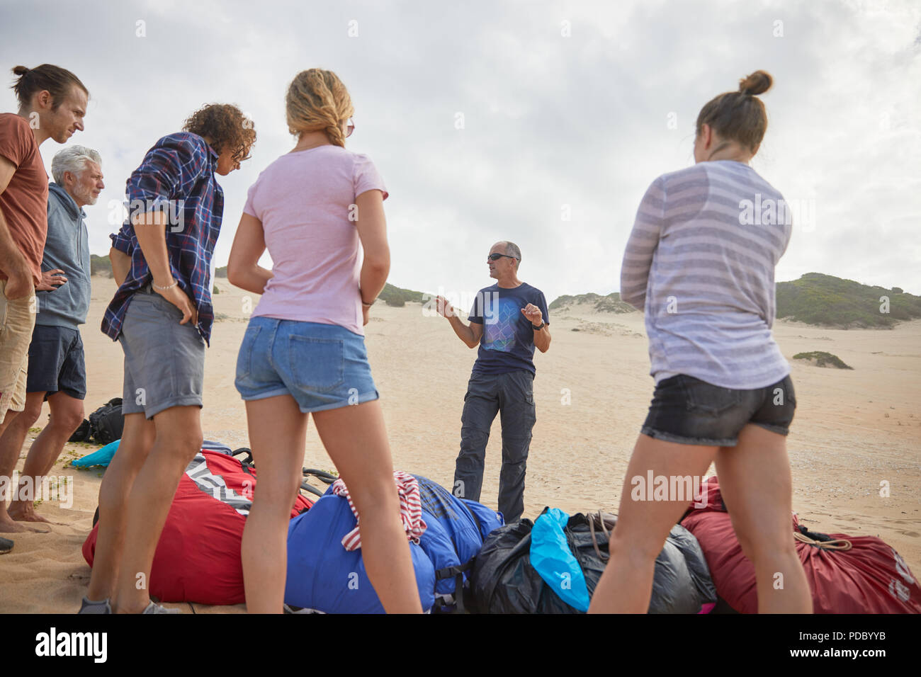 Maschio di istruttore di parapendio a parlare con gli studenti sulla spiaggia Foto Stock