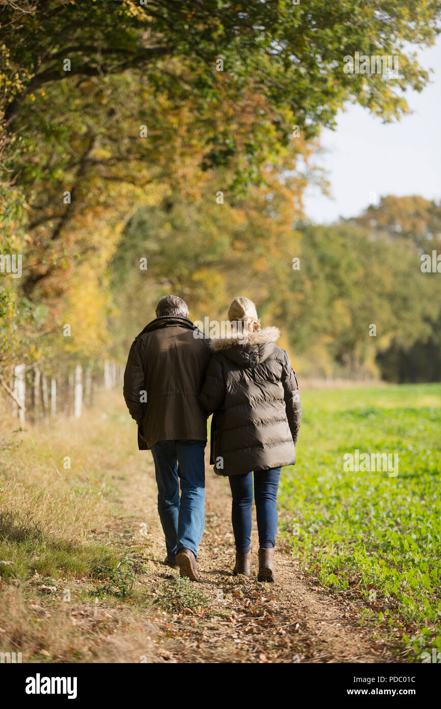 Affettuosa Coppia matura a piedi nella soleggiata, rurale campo di autunno Foto Stock