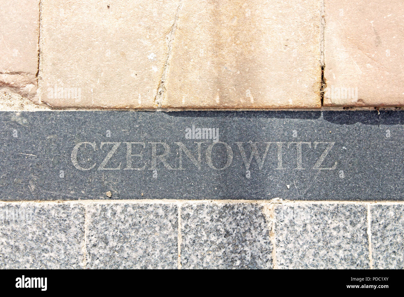 Il nome di Chernivtsi city è il tedesco (Czernowitz) nella bramma in asfalto lungo Olga Kobylianska Street, Chernivtsi, Ucraina Foto Stock