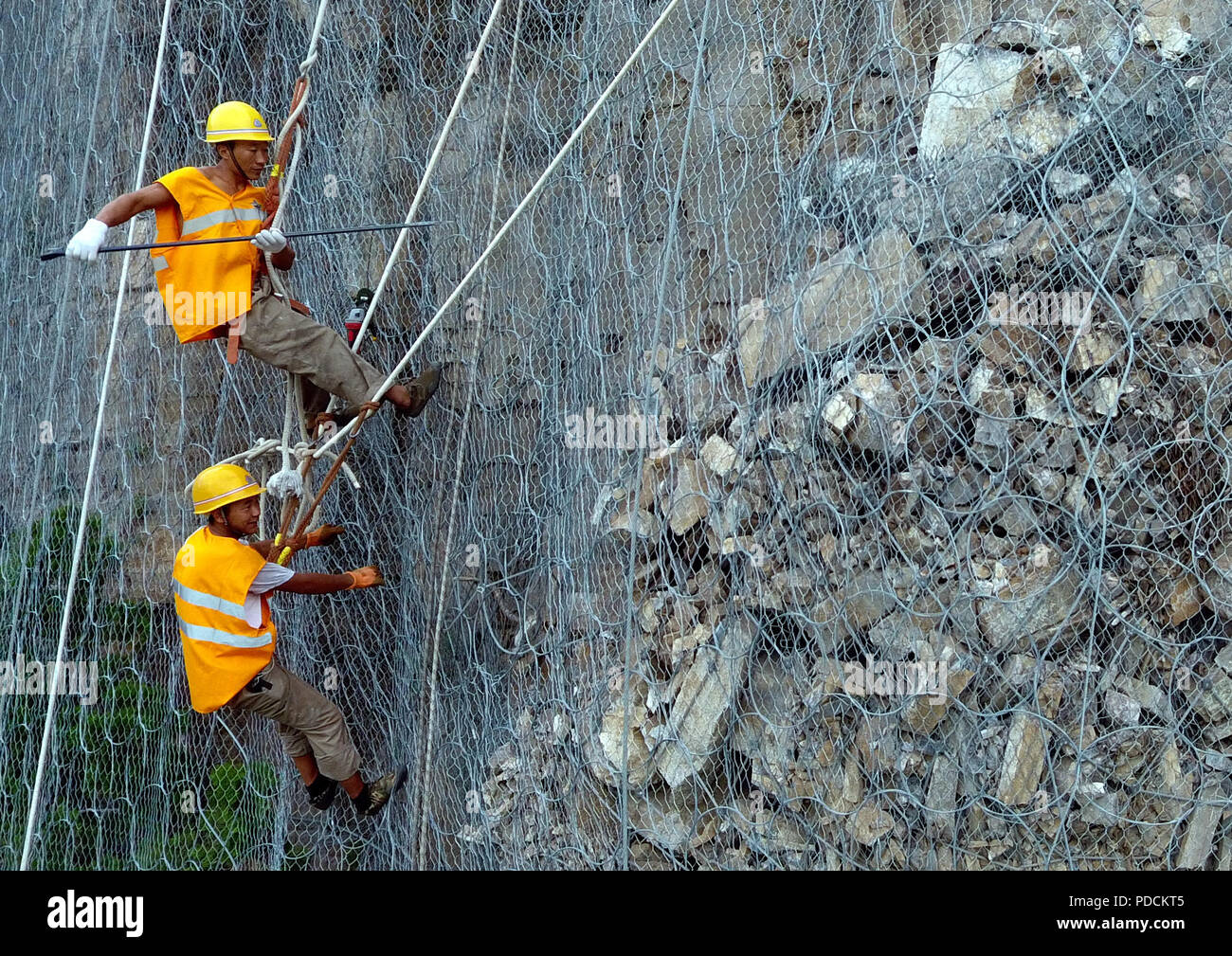 Zhengzhou. Il 9 agosto, 2018. I membri dello staff salire verso il basso di una rupe per eliminare il rischio di caduta di massi al di sopra di un tunnel della ferrovia Houma-Yueshan nella Cina centrale della Provincia di Henan, e il Agosto 9, 2018. Manutenzione ferroviaria i lavoratori lavorano sulla scogliera a chiare rocce allentati al di sopra di un tunnel ferroviario qui durante la stagione di inondazione. Credito: Li Jianan/Xinhua/Alamy Live News Foto Stock