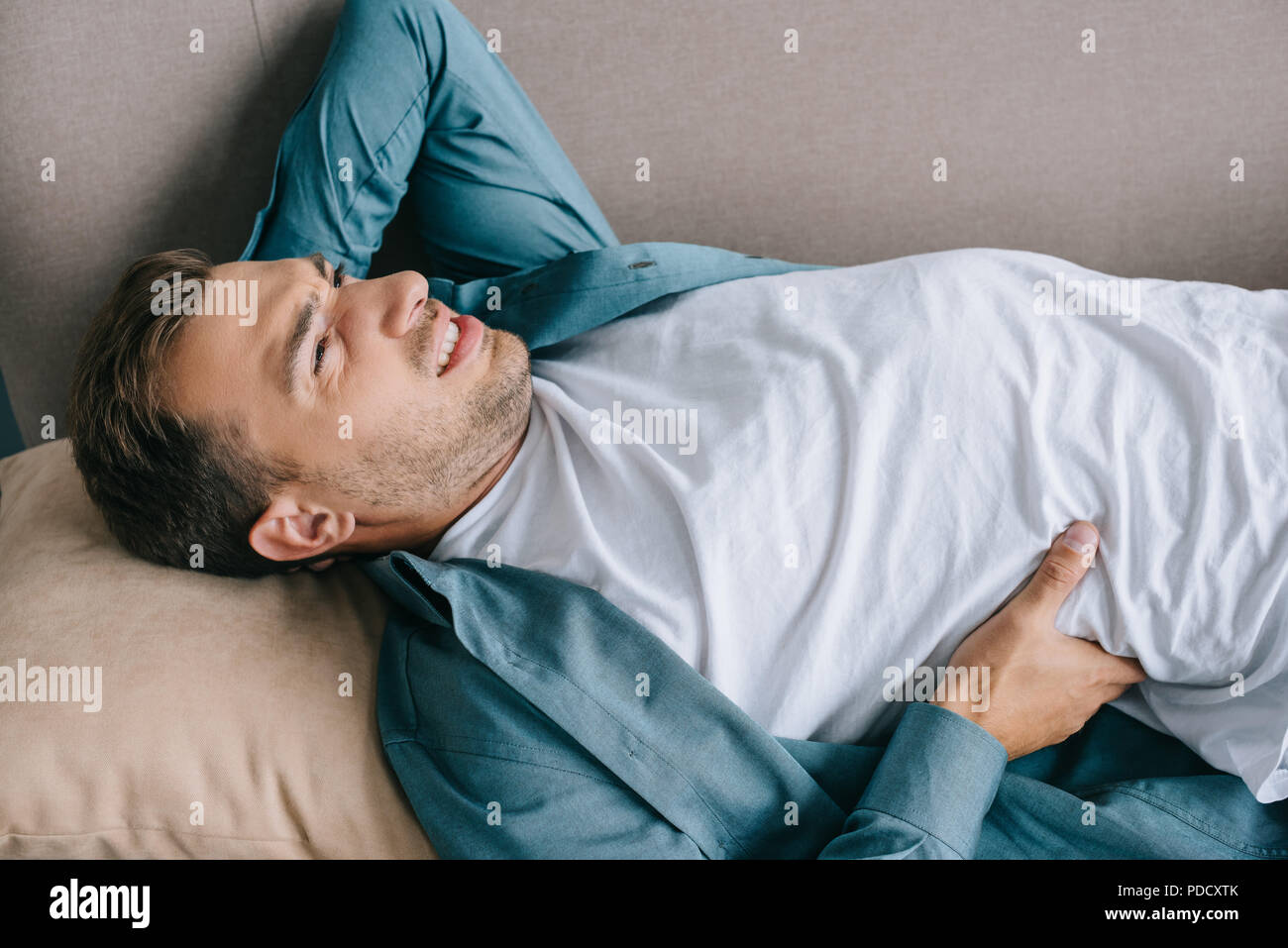 Giovane uomo che soffre di dolori alla schiena e disteso sul lettino Foto Stock
