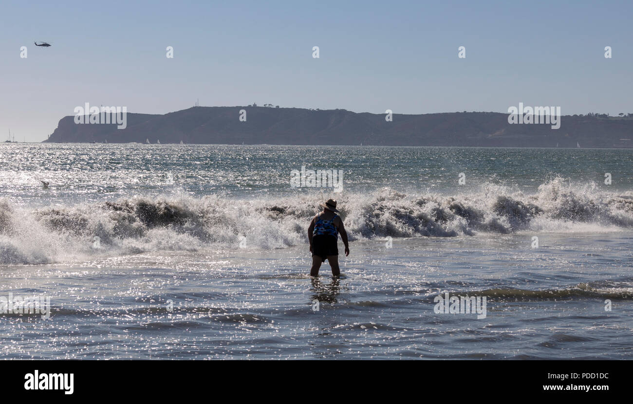 Una persona in piedi al mare come le onde si infrangono su Coronado Beach, San Diego. Foto Stock