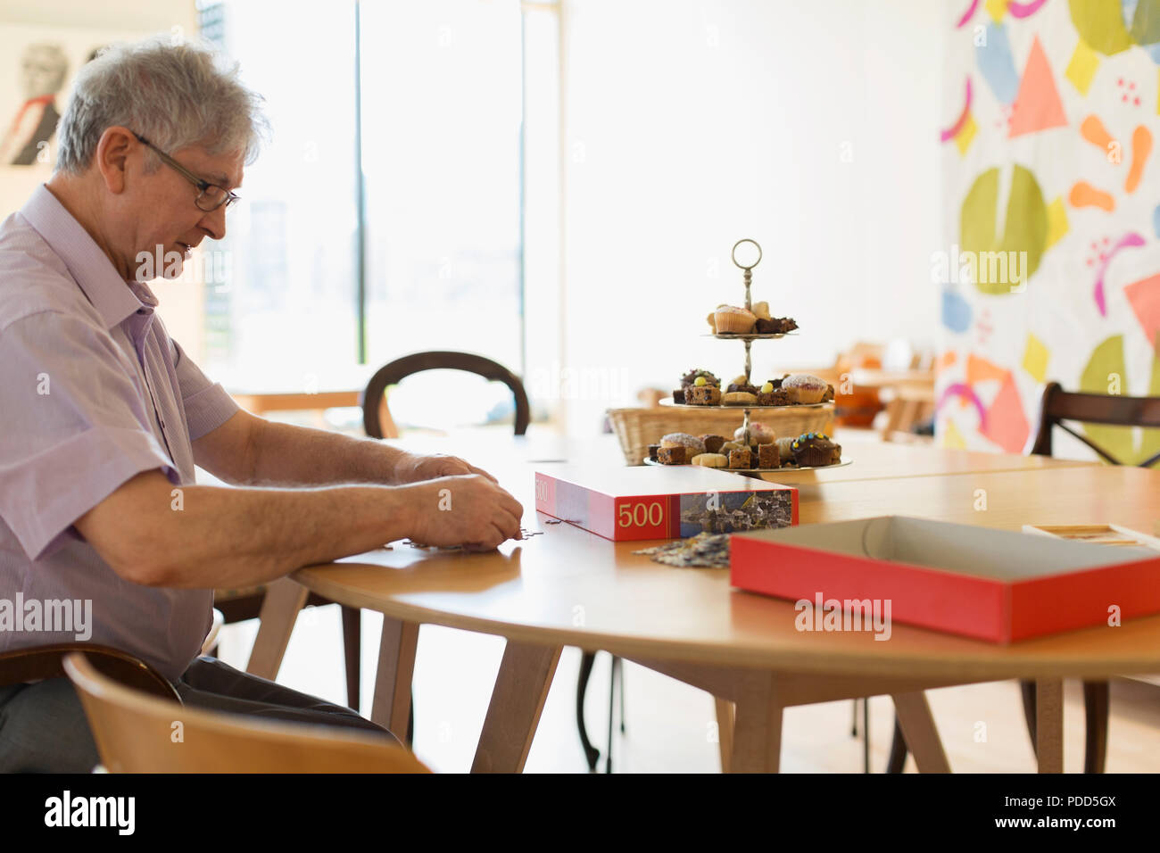 Senior uomo assemblaggio di puzzle a tavola nel centro comunitario Foto Stock