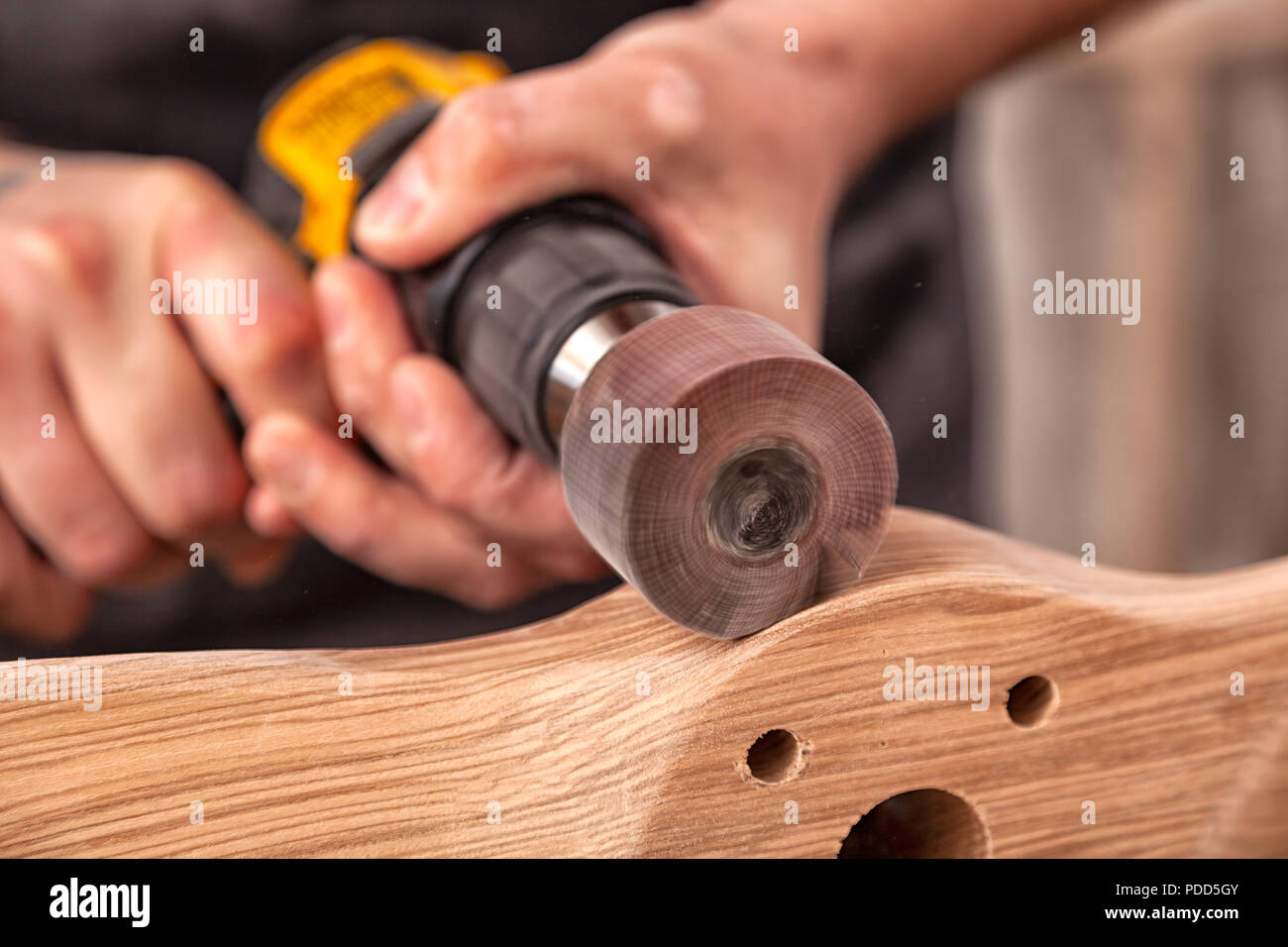 Close up di un giovane falegname builder è uguale a lucidi tavola di legno con una macchina lucidatrice o la levigatrice rotoorbitale in officina Foto Stock