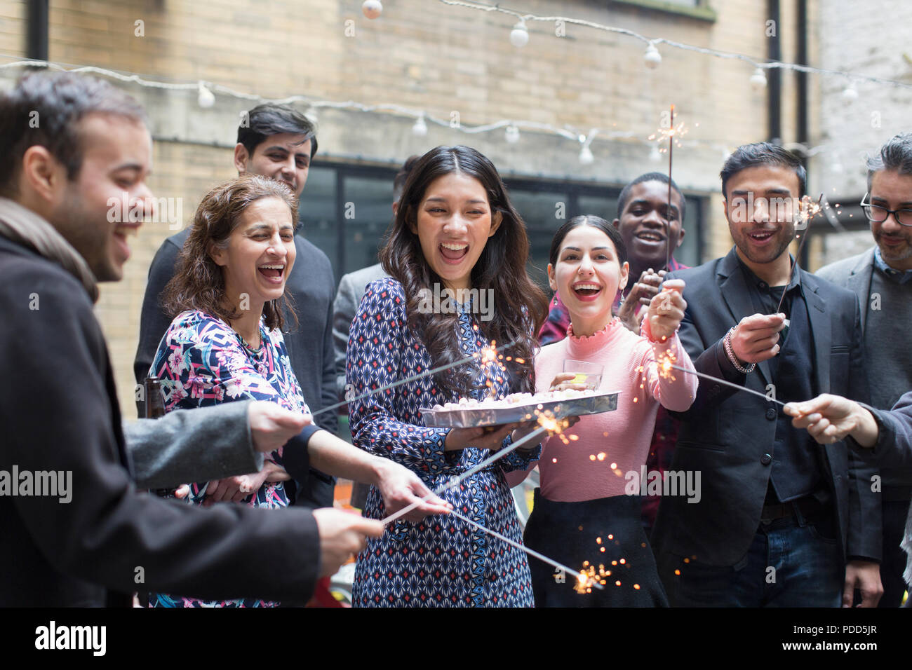Amici celebrando con donna holding torta di compleanno Foto Stock
