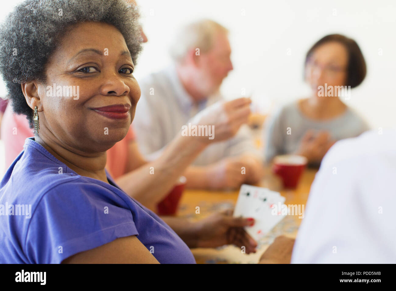 Ritratto fiducioso donna senior giocando a carte con gli amici nel centro comunitario Foto Stock