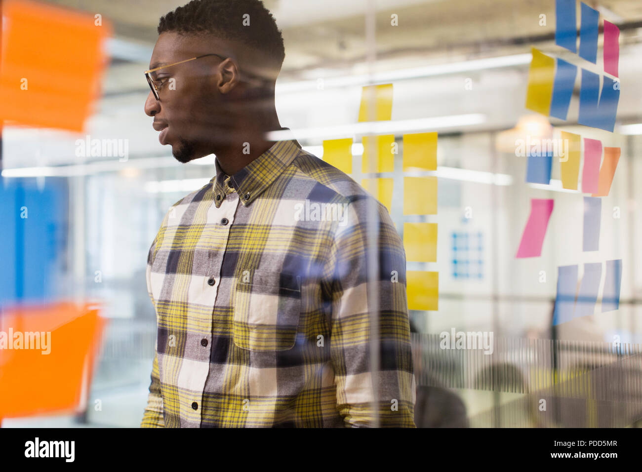 Imprenditore creativo brainstorming, utilizzando note adesive a finestra di ufficio Foto Stock