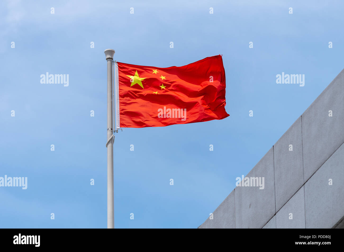 Bandiera nazionale della Repubblica popolare di Cina in volo da un palo sulla parte superiore di un edificio Foto Stock