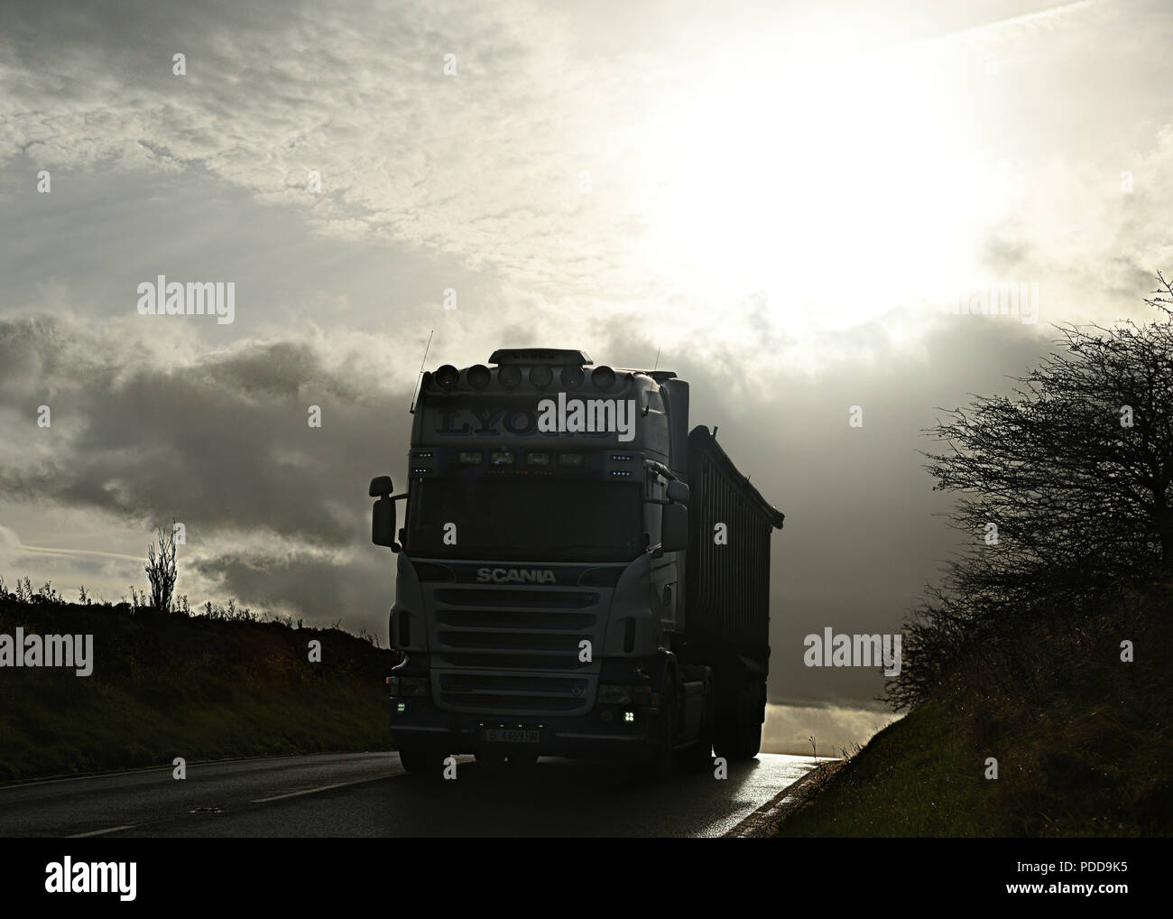 Scania ribaltabile alla rinfusa sul paese strada in inverno al crepuscolo Foto Stock