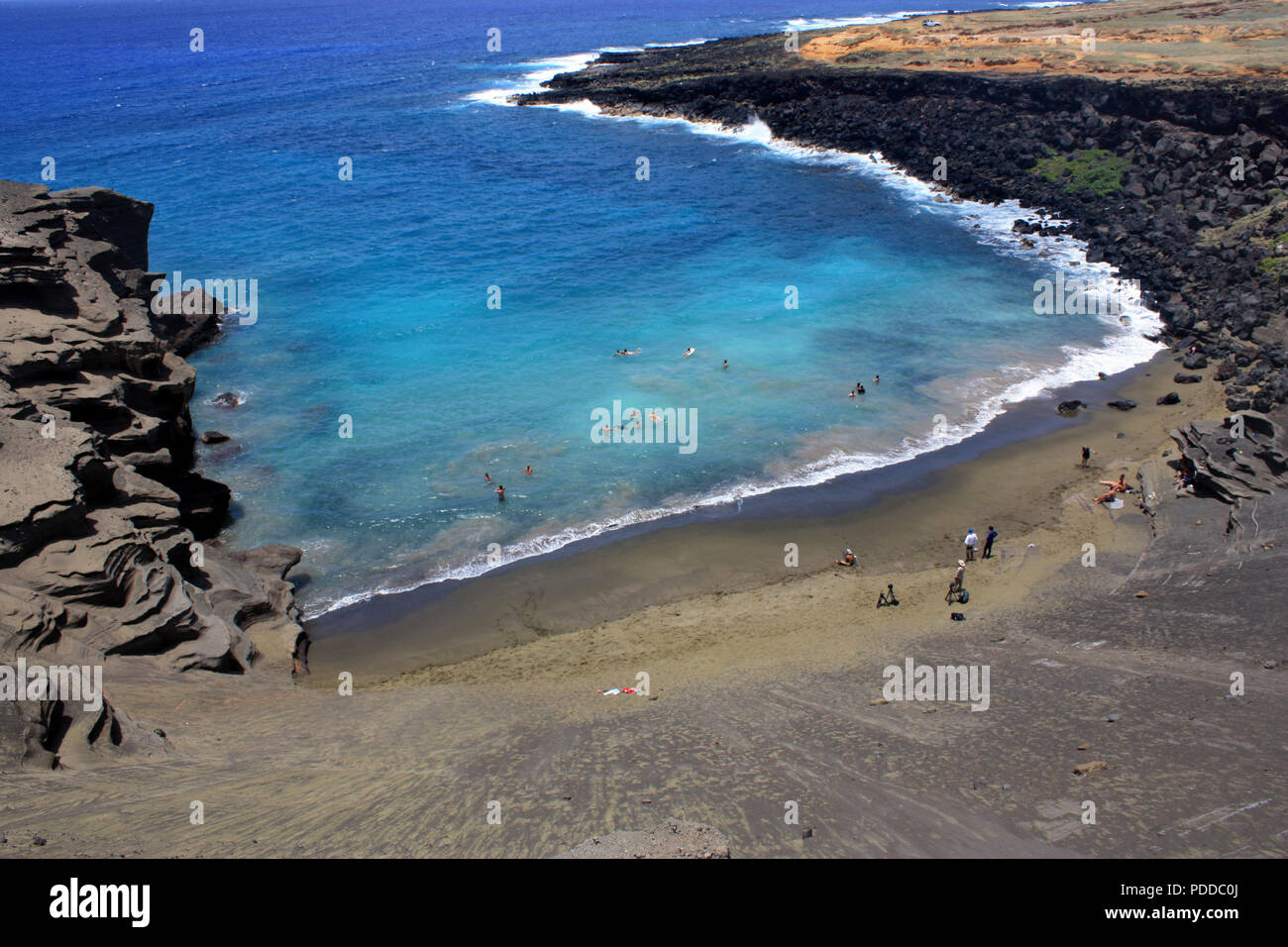 Vista di Papakolea Beach, noto anche come il verde della spiaggia di sabbia, dalla parte superiore del cono di scorie riempito con le persone nuotare e rilassarsi sulla spiaggia. Foto Stock