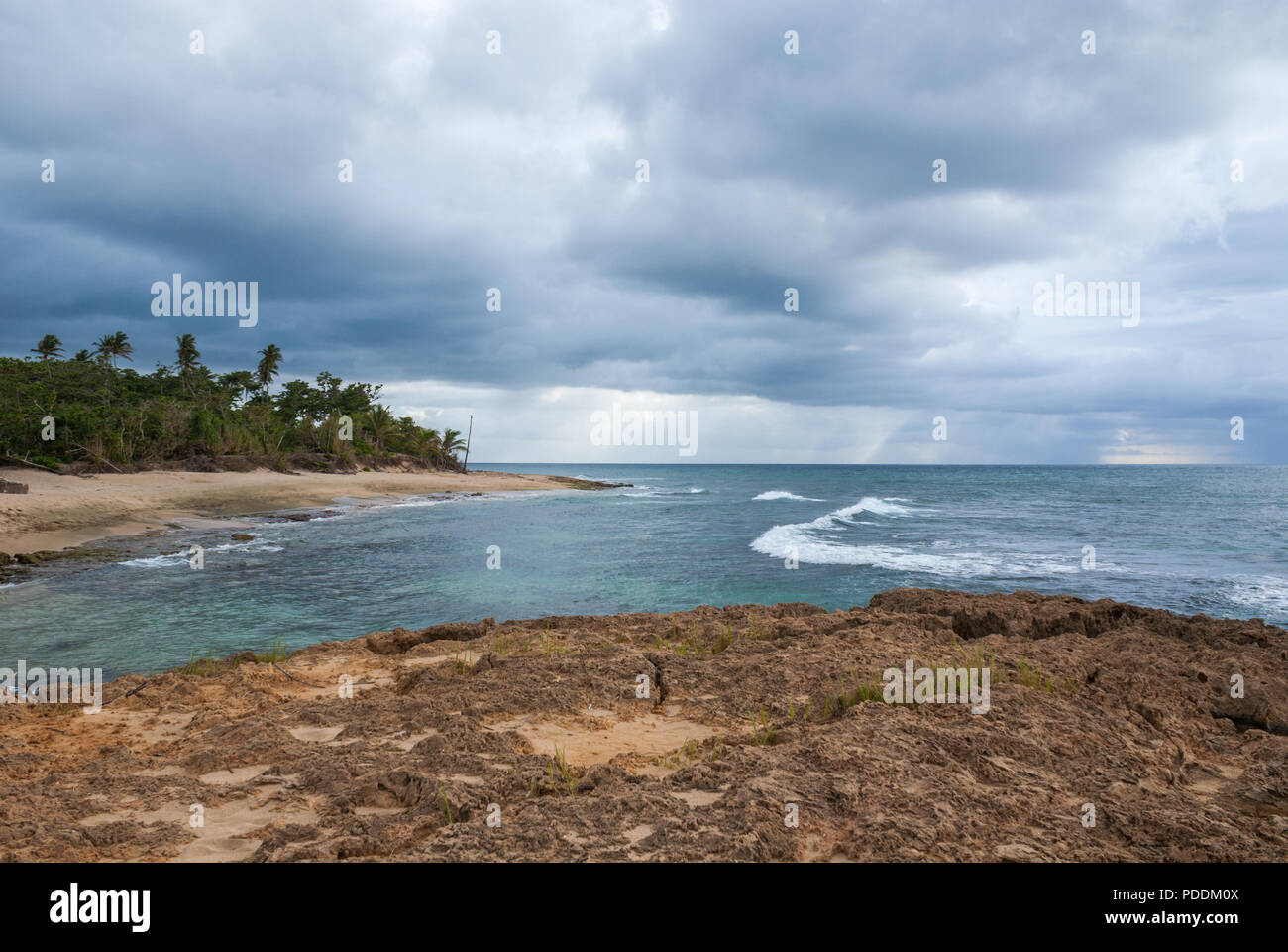 Vista di una spiaggia da una barriera corallina con luce che attraversa il cielo nuvoloso di Aguadilla, Puerto Rico Foto Stock