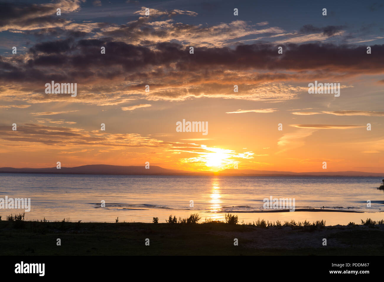 Un bel tramonto e skyscape su un lago, Lough Neagh, N.Irlanda. Foto Stock