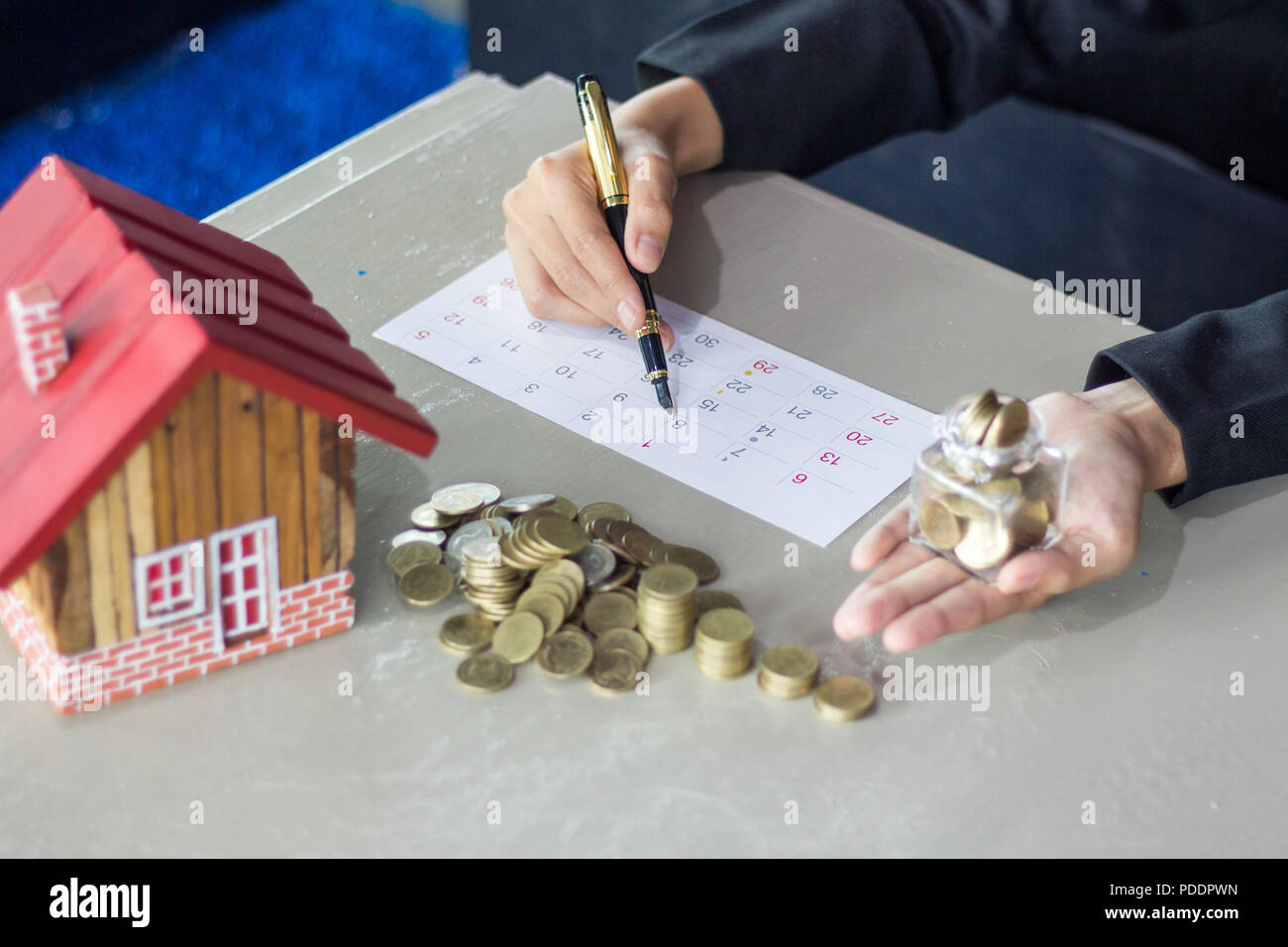 Le donne prendere appunti sul risparmio mensile, risparmi soldi jar piena di monete concetto di risparmio o di investimento per una casa. Foto Stock