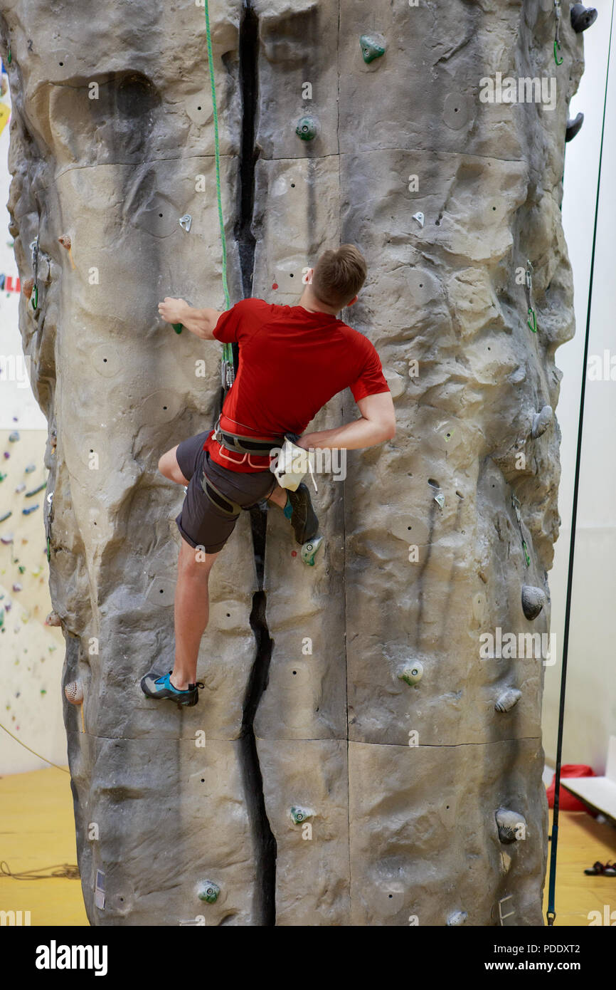Foto dal retro del maschio di arrampicata boulder in palestra Foto Stock