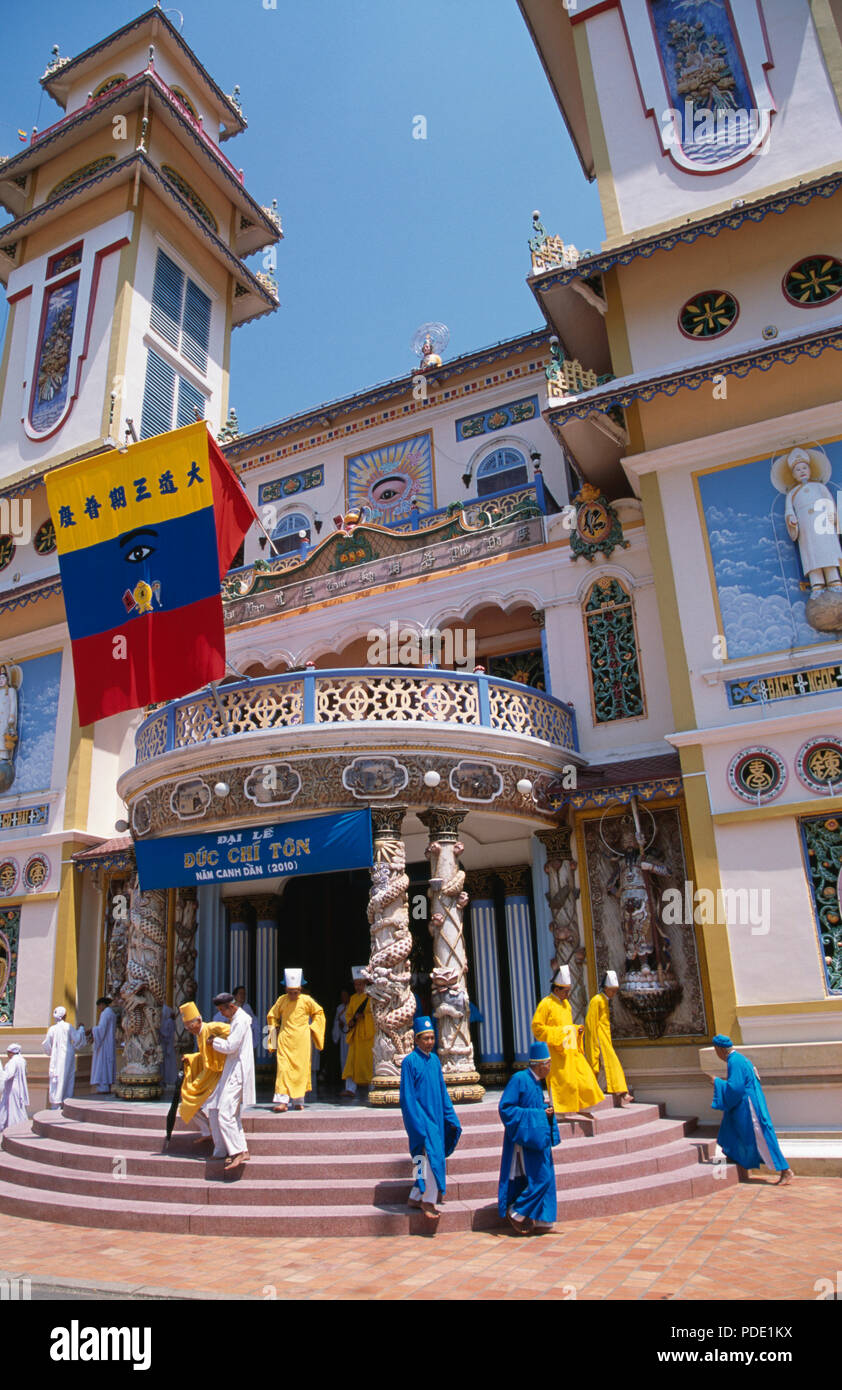 I monaci in vesti colorati sui passi al Gran Tempio Cao Dai, Long Hoa, a Tay Ninh vicino a Ho Chi Minh City in Vietnam per solo uso editoriale Foto Stock
