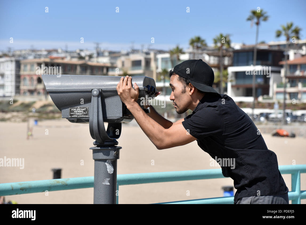 Un uomo asiatico cercando anche se il binocolo sul molo sulla spiaggia. Exclusive royalty free persone stock foto. Foto Stock