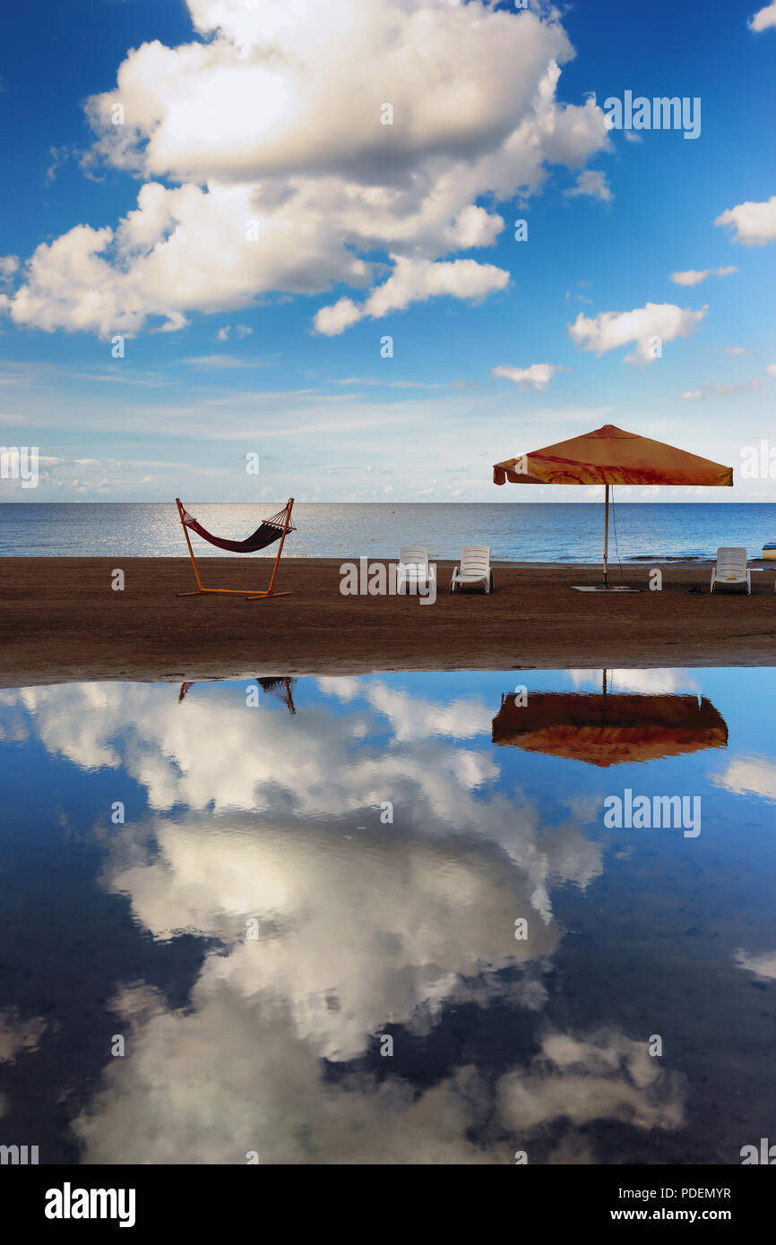 Amaca con un ombrellone e sedie su una stretta striscia di sabbia sulla Foto Stock