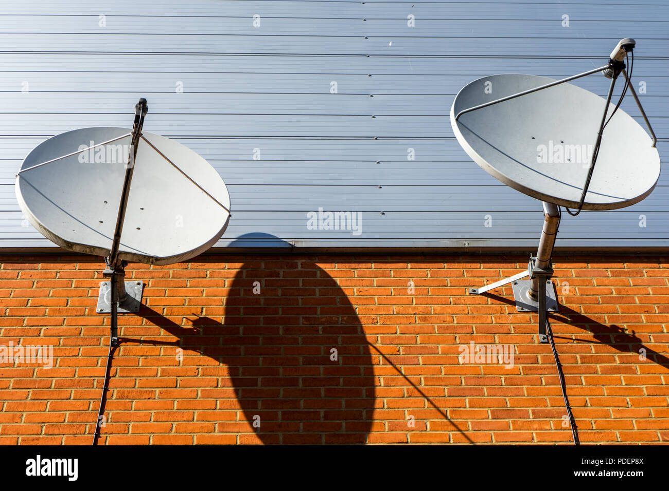 Due antenne paraboliche sul muro di mattoni Foto Stock