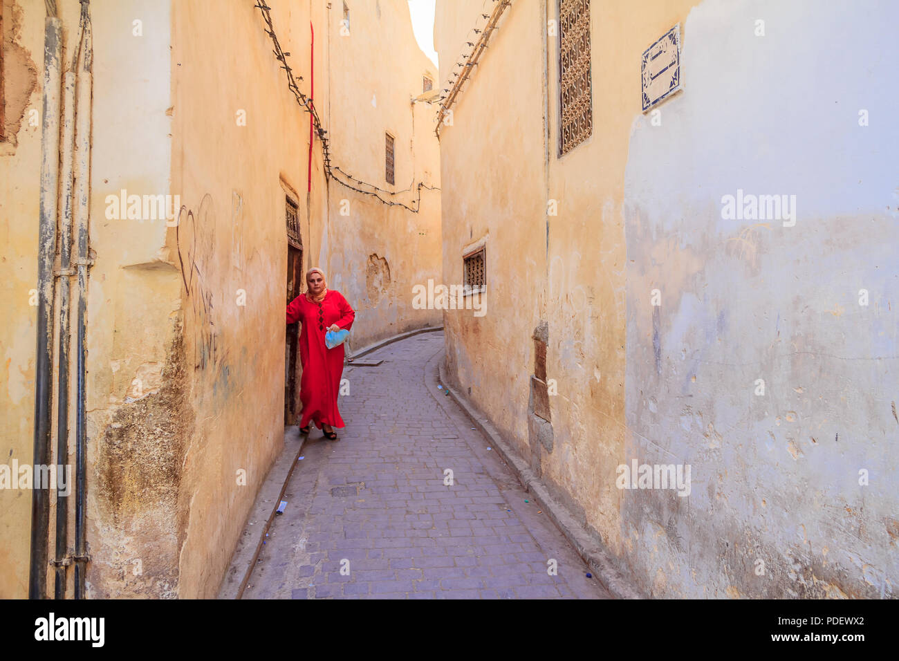 Fes, Marocco - 11 Maggio 2013: donna che indossa un kaftan, Marocchino tradizionale abbigliamento, uscendo in una stretta strada di Fes Medina in Marocco Foto Stock