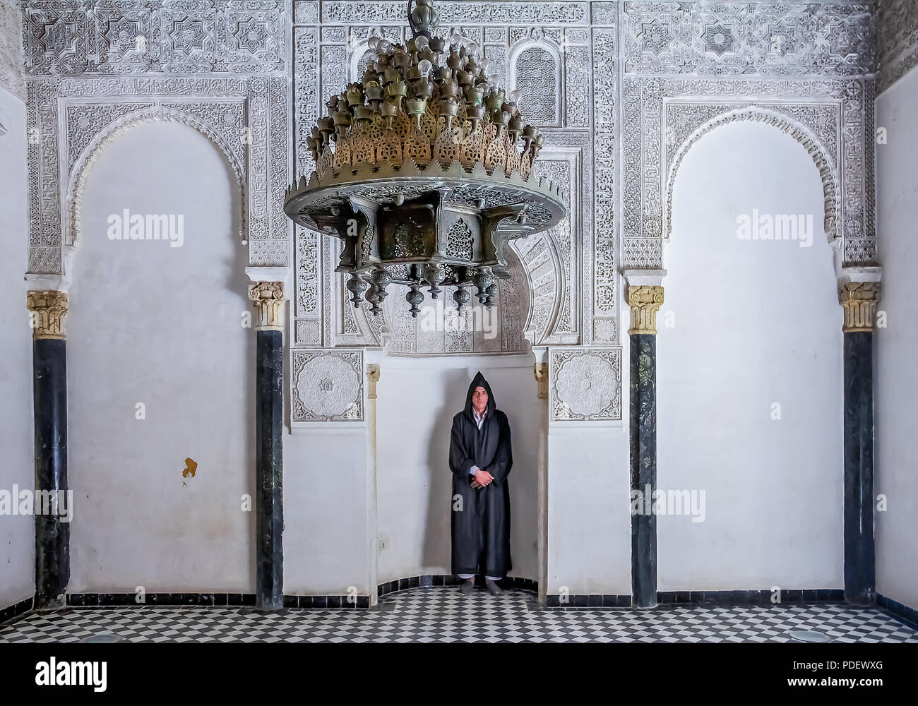 Fes, Marocco - 11 Maggio 2013: l'uomo a Berber abbigliamento in una nicchia nel cortile interno del XIV secolo El Attarine Medersa di Fez, Marocco Foto Stock