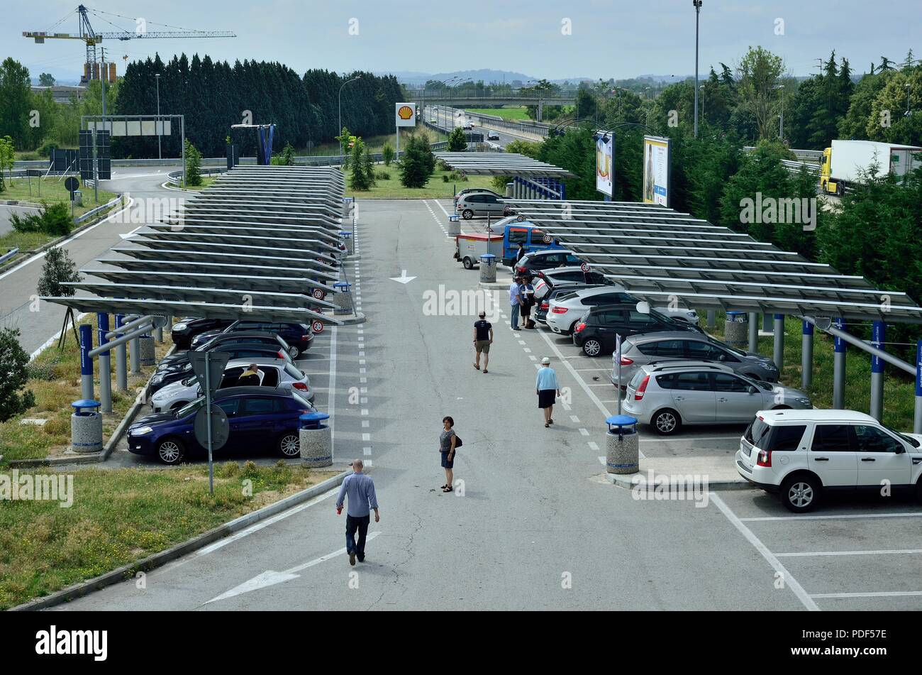 Area parcheggio per auto / Parcheggio auto coperto con pannelli solari vicino al distributore di benzina Shell / Gas / Stazione di benzina lungo il lato di una autostrada vicino a Pisa, Italia Foto Stock