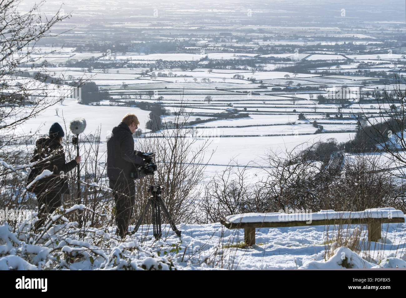 Un uomo della telecamera e operatore audio look-out attraverso la Nibberdale area di straordinaria bellezza naturale come la neve cade nello Yorkshire, Regno Unito Foto Stock