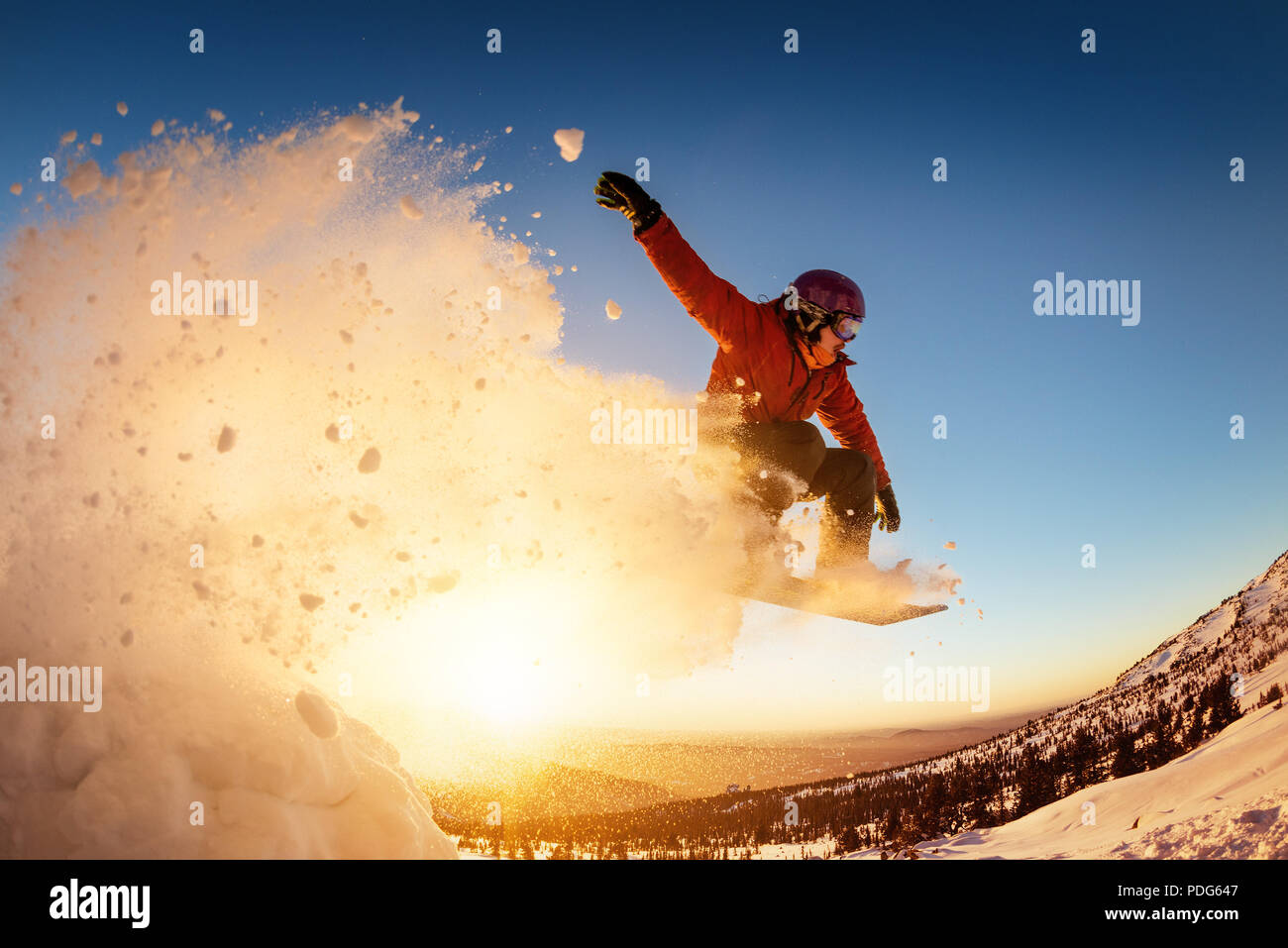 Snowboarder salta al tramonto con polvere di neve Foto Stock