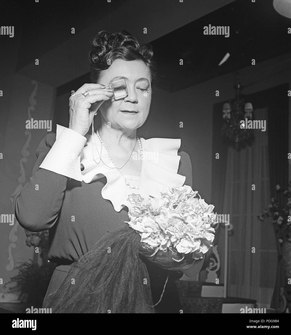 1940s donna con occhiali. Una signora più anziana sta guardando qualcosa attraverso un monocolo. Svezia 1944 Foto Kristoffersson/K96-5 Foto Stock