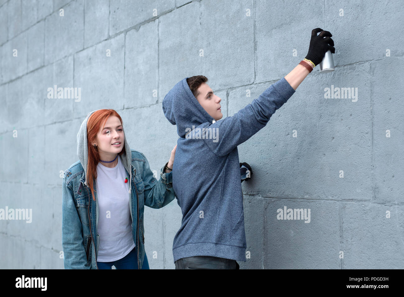 Piacevole coppia giovane disegnare graffiti sul muro Foto Stock