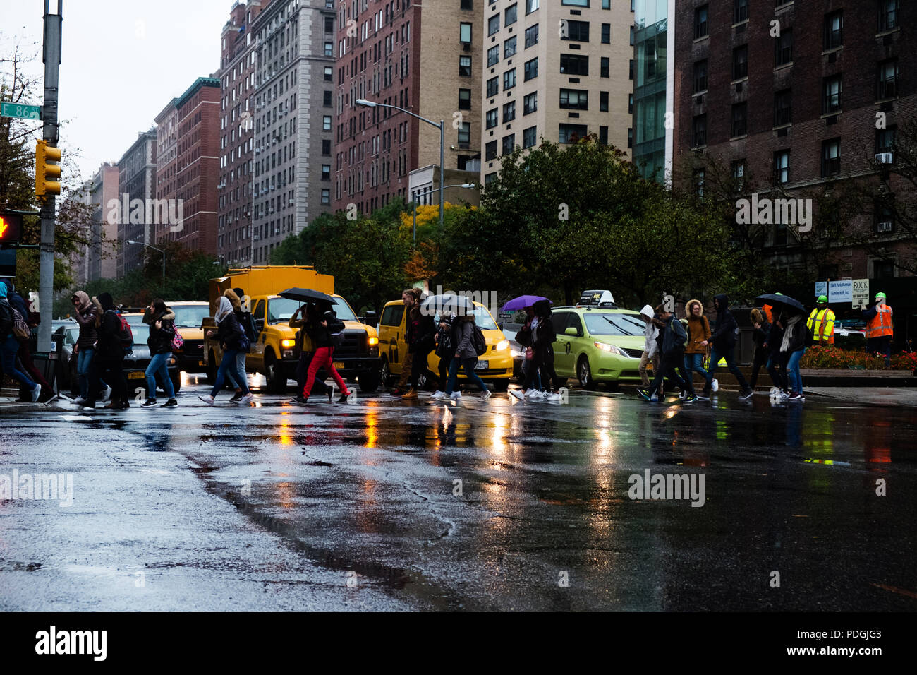 Attraversamento di una New York street in un giorno di pioggia Foto Stock